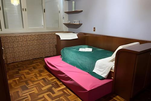 a room with a bed with a green and pink blanket at Apto central na Via Del Vino in Bento Gonçalves
