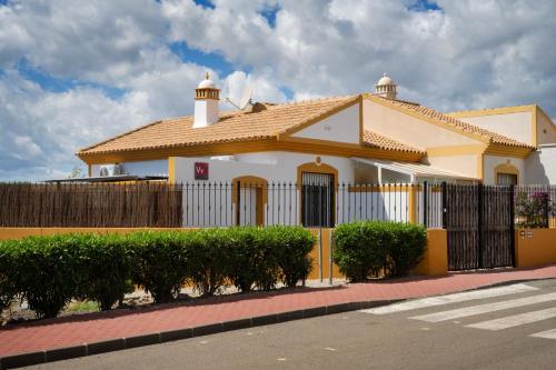 a yellow and white house with a fence and bushes at Casa Coco in Mazarrón