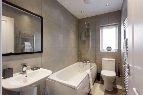 a bathroom with a sink and a tub and a toilet at Heath Reach - Just a short distance to Tower Park in Poole