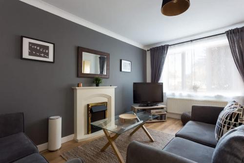 een woonkamer met een bank, een tv en een open haard bij Palma - Hamworthy Beach and Park Short Walk Away in Poole