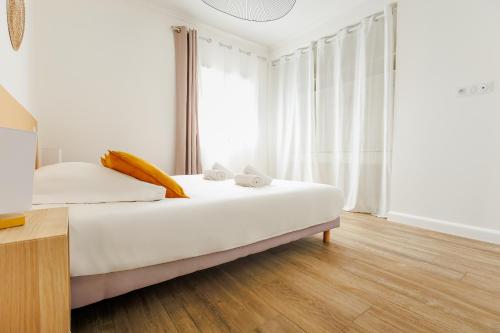 een slaapkamer met een bed met witte lakens en gele kussens bij Casamea - T2 A Tavagna in Talasani