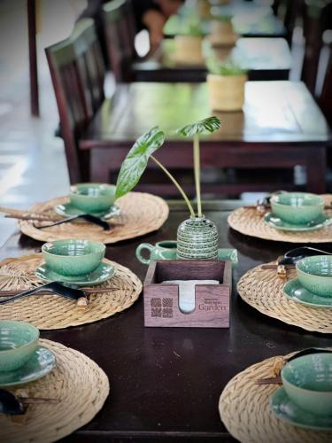 a table with plates and cups and a potted plant at Amazing Ninh Binh Garden in Xuân Sơn