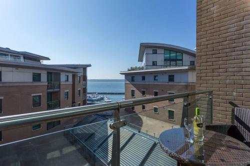 a balcony with a table and a view of the ocean at Reflections - Balcony Views of Poole Harbour in Poole