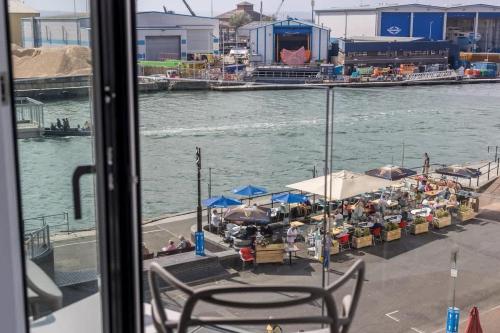a balcony with tables and umbrellas next to the water at Endless Summer - Spacious Living Space on Poole Quay in Poole