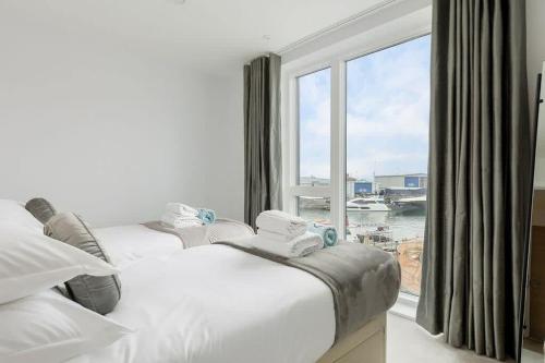 two beds in a hotel room with a large window at Endless Summer - Spacious Living Space on Poole Quay in Poole