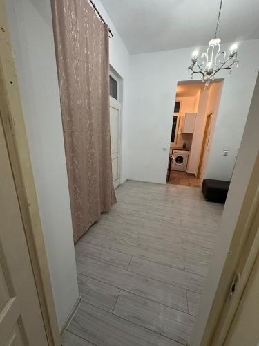 a hallway with a chandelier and a room with white walls at Apartament Eugen in Băile Govora