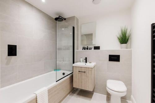 a bathroom with a toilet and a sink and a shower at Aurora South - Short Walk to Ashley Cross in Poole