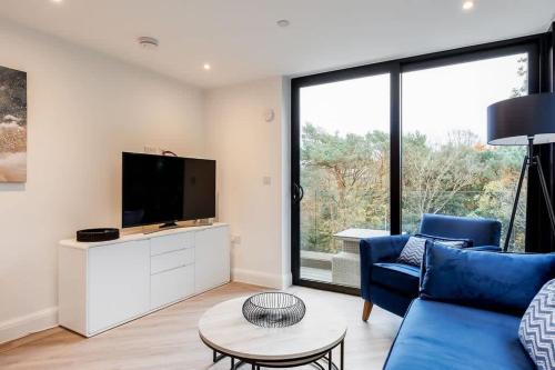 a living room with a blue couch and a tv at Aurora South - Short Walk to Ashley Cross in Poole
