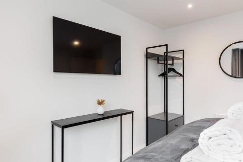 a bedroom with a bed and a tv on the wall at Aurora South - Short Walk to Ashley Cross in Poole