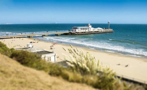 a view of a beach with a pier and the ocean at Aurora South - Short Walk to Ashley Cross in Poole