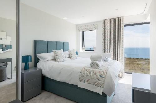 a bedroom with a large bed and a large window at Beachcliff - On the Seafront with Two Balconies in Bournemouth