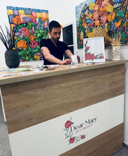 a man sitting at a counter with a painting at Dear Mary, B&B romantico vicino Lecce nel cuore del Salento in San Cesario di Lecce