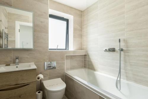 a bathroom with a tub and a toilet and a sink at Beachcliff - On the Seafront with Two Balconies in Bournemouth