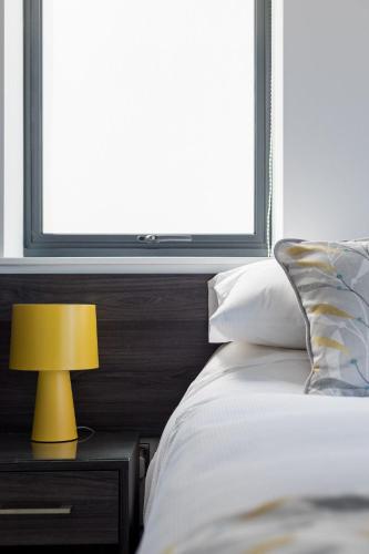 a bedroom with a bed with a yellow lamp on a night stand at Beachcliff - On the Seafront with Two Balconies in Bournemouth