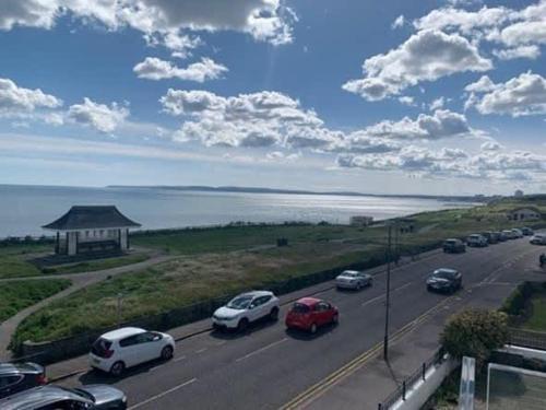 a highway with cars parked on the road near the water at Beachcliff - On the Seafront with Two Balconies in Bournemouth