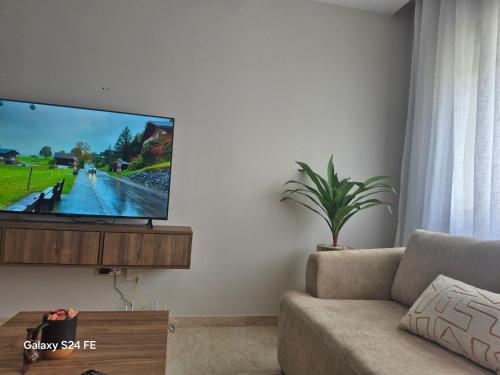 a living room with a couch and a flat screen tv at aeroperla 15 aéroport casa blanca in Nouaseur