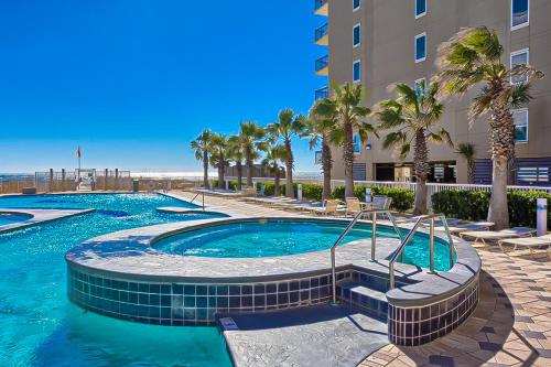 a swimming pool with palm trees and a building at Crystal Tower 705 in Gulf Shores
