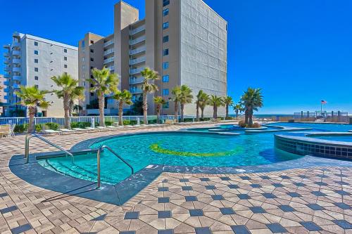 a swimming pool in front of a building with palm trees at Crystal Tower 705 in Gulf Shores