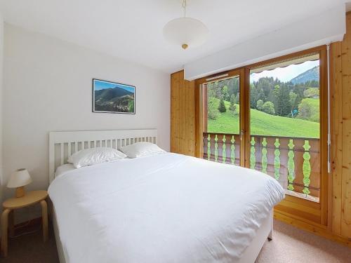 une chambre avec un lit blanc et une grande fenêtre dans l'établissement Grand Cerf 62, à Saint-Jean-dʼAulps