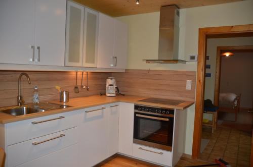 a kitchen with white cabinets and a sink and a stove at Ferienwohnung Grössenberg in Weißkirchen in Steiermark