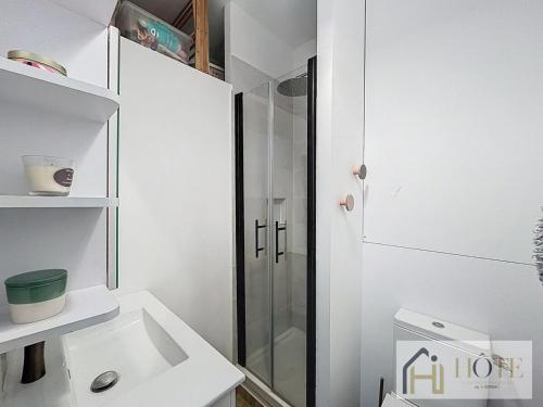 une salle de bain blanche avec une douche et un lavabo dans l'établissement Douce Escale Sea View, à Bray-Dunes