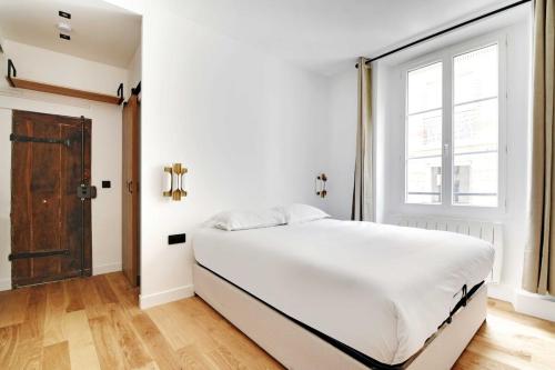 une chambre blanche avec un grand lit et une fenêtre dans l'établissement Studio-Suite 4 stars, 15m from Eiffel, Refined, à Paris