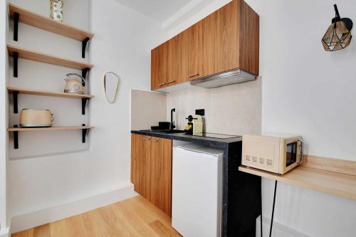 une petite cuisine avec un micro-ondes et un réfrigérateur dans l'établissement Studio-Suite 4 stars, 15m from Eiffel, Refined, à Paris
