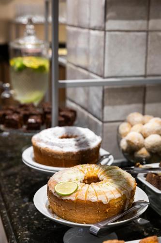 three cakes sitting on plates on a counter top at H Hotel in Balneário Camboriú