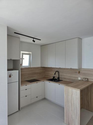a kitchen with white cabinets and a wooden counter top at Apartman Magdalena in Seoca