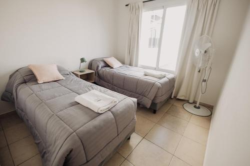 a bedroom with two beds and a fan and a window at Complejo Coirón in San Rafael