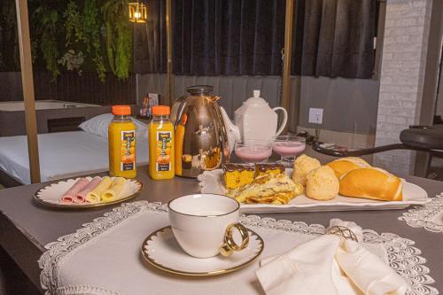 a table with a cup of coffee and a plate of food at Ragam Motel Empreendimentos Hoteleiros in Ponta Grossa
