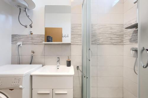 a white bathroom with a sink and a shower at Apartment Eli in Banjole