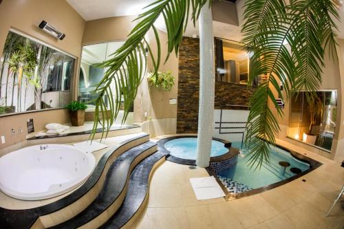 a bathroom with a bath tub and a palm tree at Ragam Motel Empreendimentos Hoteleiros in Ponta Grossa