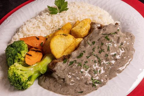 a plate of food with rice and meat and vegetables at Ragam Motel Empreendimentos Hoteleiros in Ponta Grossa