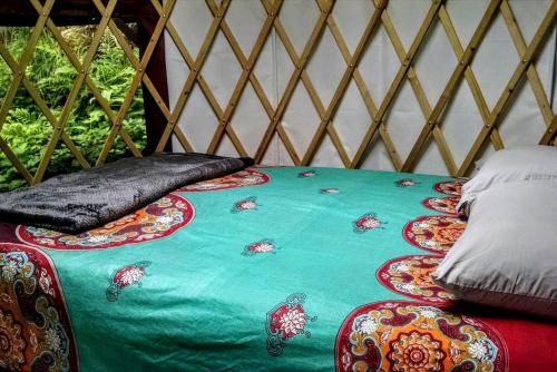 un lit dans une yourte avec une couette verte dans l'établissement Original Yurt with Complimentary Sea Kayaks for a Unique Getaway in Seward, Alaska, à Seward