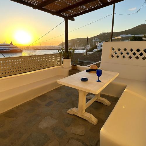 a table on a balcony with the sunset in the background at Mykonos Seaview Nests - Tourlos Getaways in Tourlos