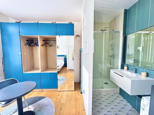La salle de bains est pourvue de placards bleus, d'un lavabo et d'une douche. dans l'établissement Charmant appartement en plein cœur du centre-ville, à Amiens