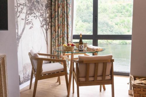 a dining room table with two chairs and a bottle of wine at Treixadura in Pincelo