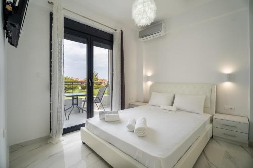 a white bedroom with a bed and a balcony at SithoniaRS Sea Nomad Luxury Maisonette in Nikiti