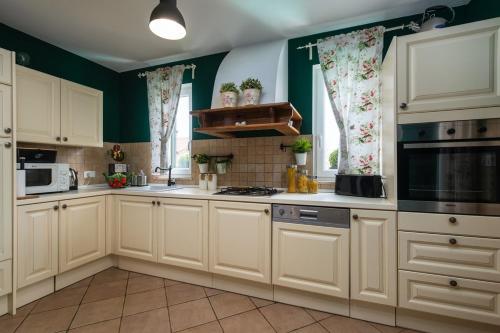 a kitchen with white cabinets and green walls at Villa Laura in Krnica