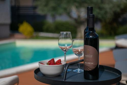 a bottle of wine and two glasses and a bowl of strawberries at Villa Laura in Krnica
