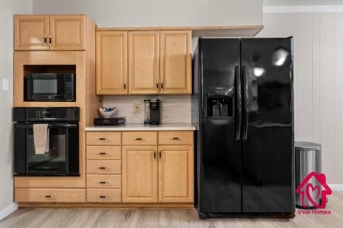 a kitchen with a black refrigerator and wooden cabinets at Chapala Charm 6BR Family Oasis - An Irvie Home in Albuquerque