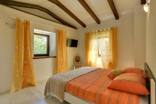 a bedroom with a bed with an orange comforter and a window at Villa Bella in Paz