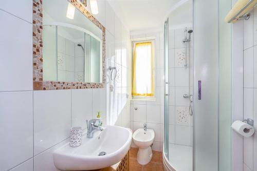 ein weißes Badezimmer mit Waschbecken und Dusche in der Unterkunft Apartments Ivonne in Ližnjan