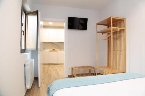 a bedroom with a bed and a tv and a kitchen at La Estrella de Tarsis in Santillana del Mar