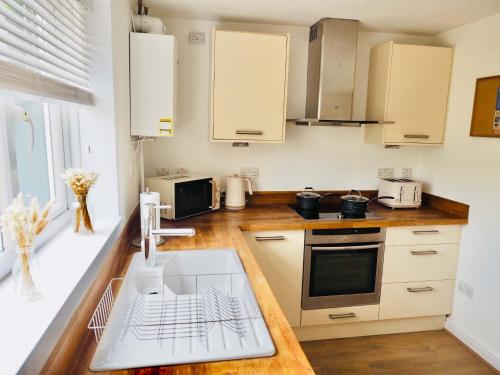 cocina con armarios blancos, fregadero y encimera en Convenient 2 Bedroom Home with Parking in Taunton, en Taunton
