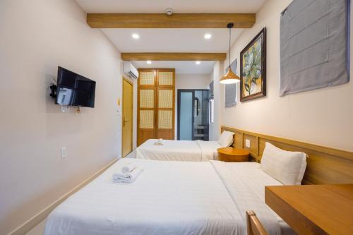 a hotel room with two beds and a tv at Lotus Home Corner & Rooftop in Phu Quoc
