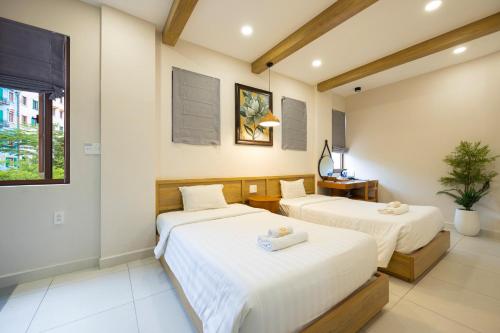 two beds in a room with white walls at Lotus Home Corner & Rooftop in Phu Quoc