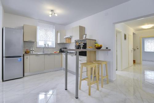 a kitchen with white cabinets and a counter with stools at Villa Rudy in Štinjan