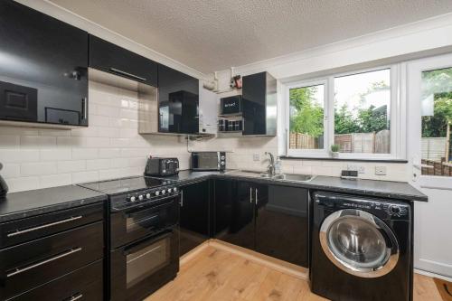 cocina con armarios negros y lavadora en Comfortable 2 Bedroom Home with Parking in Taunton, en Taunton